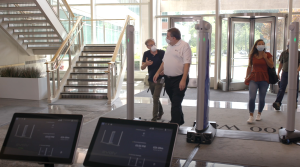 Image: Two men passing through a weapons detection system at office entrance.
