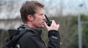 Man in a black jacket using a walkie talkie radio